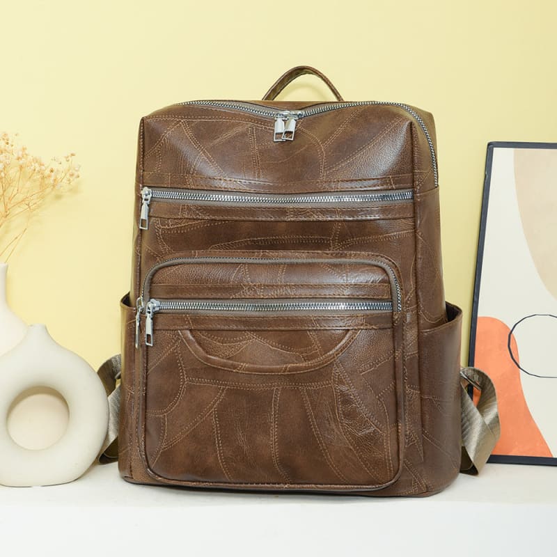 Brown leather backpack with multiple zippered compartments.