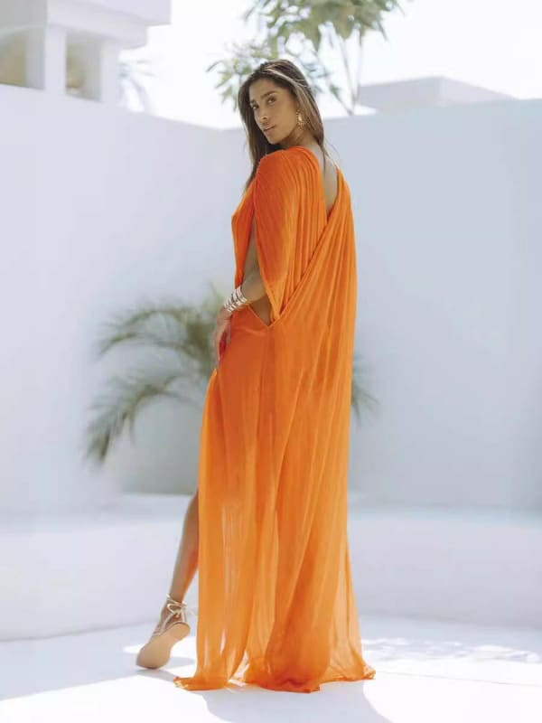 Flowing orange maxi dress with loose sleeves and a side slit.