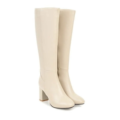 Pair of knee-high cream-colored boots with chunky heels.