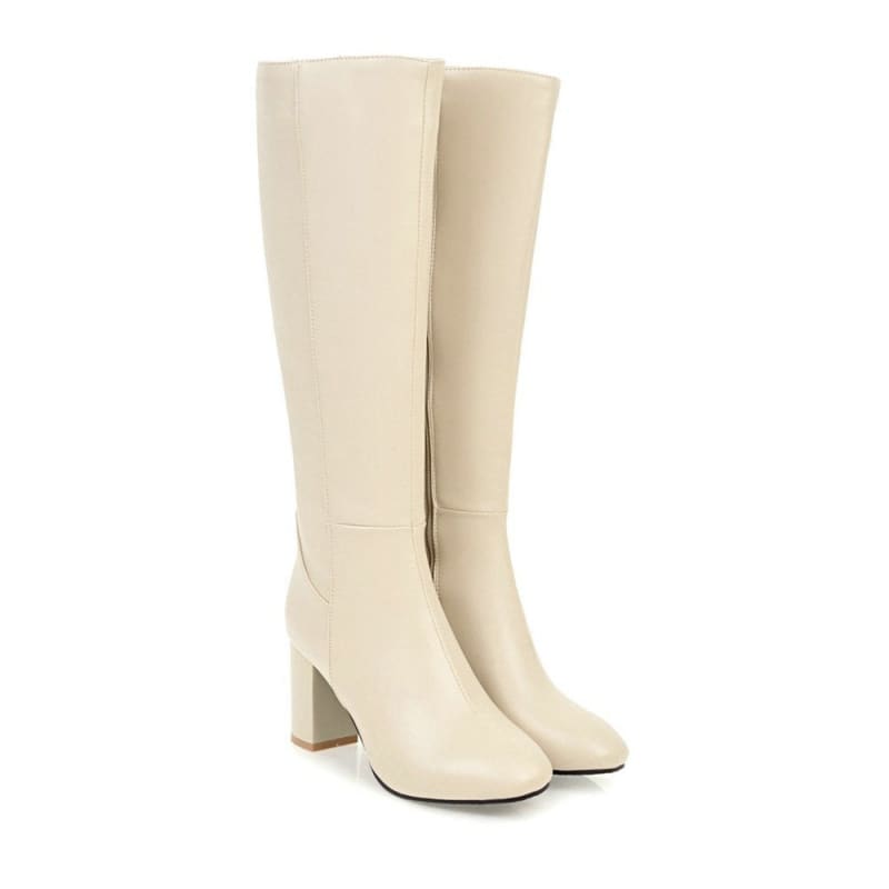 Pair of knee-high cream-colored boots with block heels.