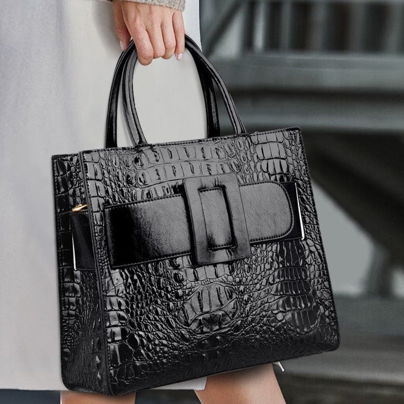 Black leather handbag with crocodile texture and a prominent front bow detail.