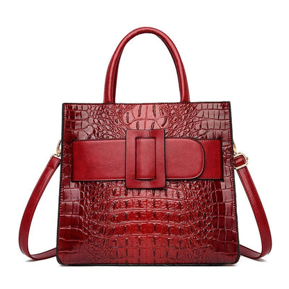 Red leather handbag with crocodile texture and a prominent buckle detail.