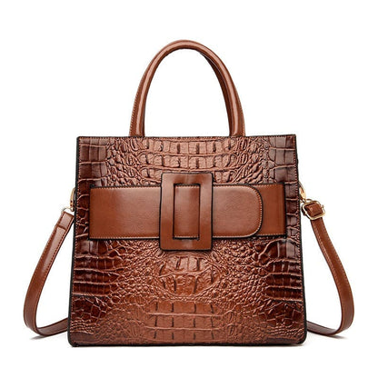 Brown leather handbag with crocodile texture and a prominent buckle detail.