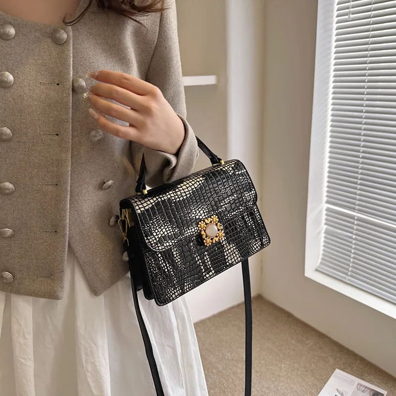 Black and silver textured crossbody bag with gold hardware in womens crocodile pattern.