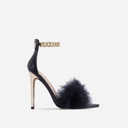 High-heeled sandal with black feathers and a gold chain ankle strap.