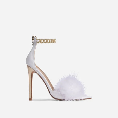 White high-heeled sandal with a fluffy fur strap and gold chain ankle strap.