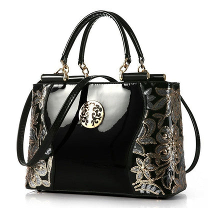 Elegant black handbag with floral embroidery and gold-tone hardware.