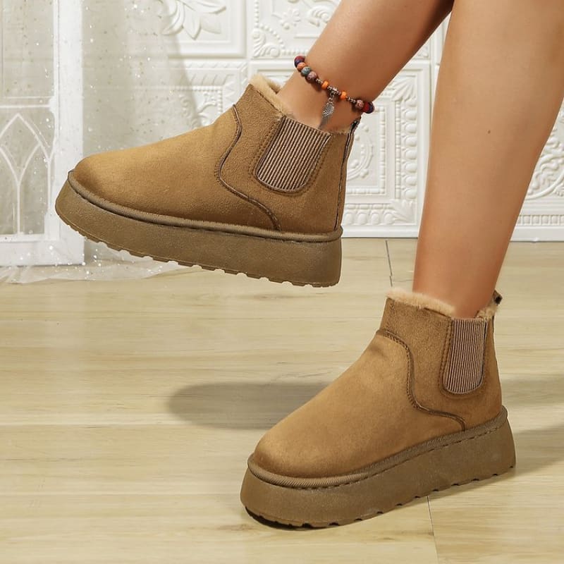 Pair of tan suede ankle boots with thick soles and elastic side panels.