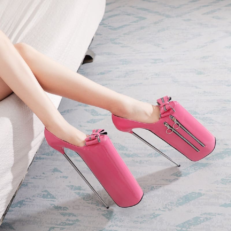 Pair of bright pink high-heeled shoes with extremely tall platforms and thin stiletto heels.